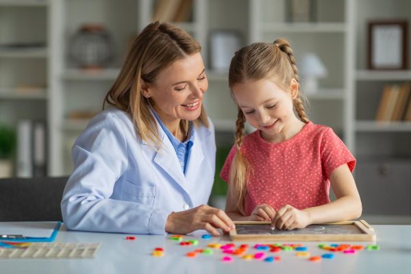 Little Girl Painting On Mini Chalkboard During Meeting With Child Development Specialist